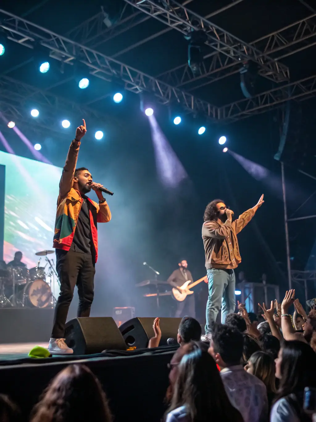 A vibrant photograph capturing a live performance organized by LES VERTEBREES, showcasing artists on stage with an engaged audience in the background, highlighting the energy and community involvement.
