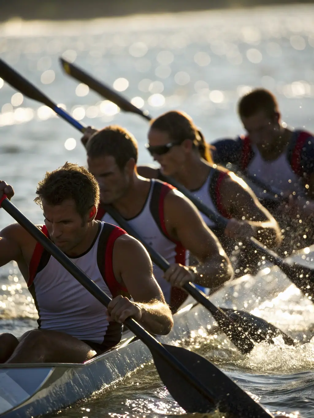 A group of rowers in a training session on a calm lake, focusing on synchronized rowing technique, early morning light.